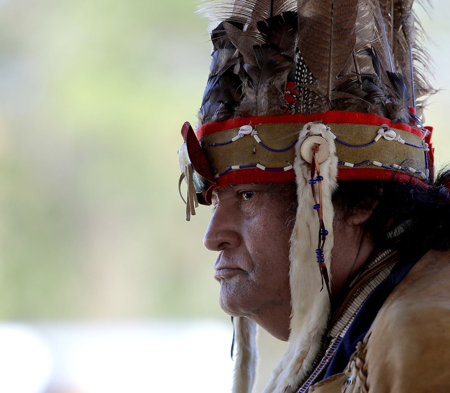 The chief in full feathered headdress — profile at a tribal gathering